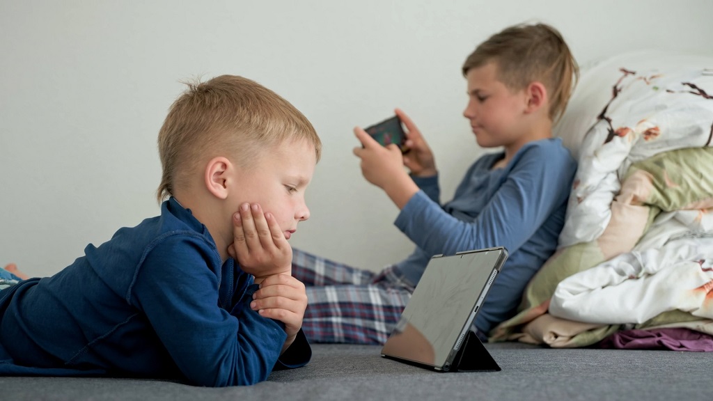 Dečaci leže i koriste digitalne uređaje, što može uticati na sposobnost fokusiranja